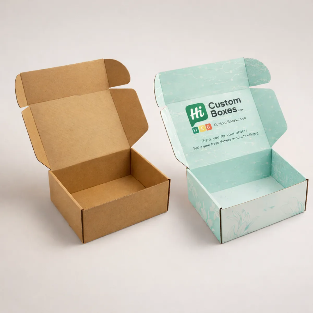 Two open cardboard mailing boxes, one natural brown kraft and one with a light blue floral lining. class=